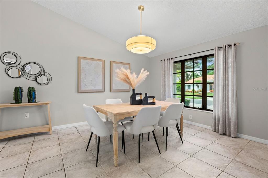 A dining room features a light wood table, white chairs, and a modern pendant light — 1318 VERMEER DRIVE, NOKOMIS, FL