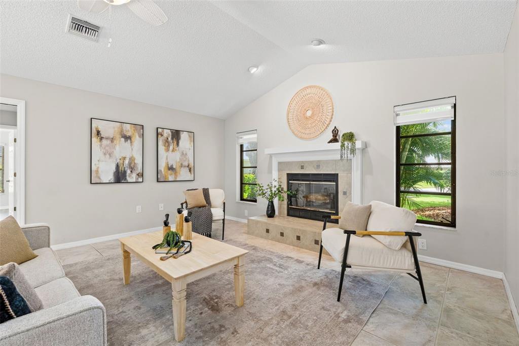 A living room features a vaulted ceiling, a tile fireplace, and light-colored furniture — 1318 VERMEER DRIVE, NOKOMIS, FL