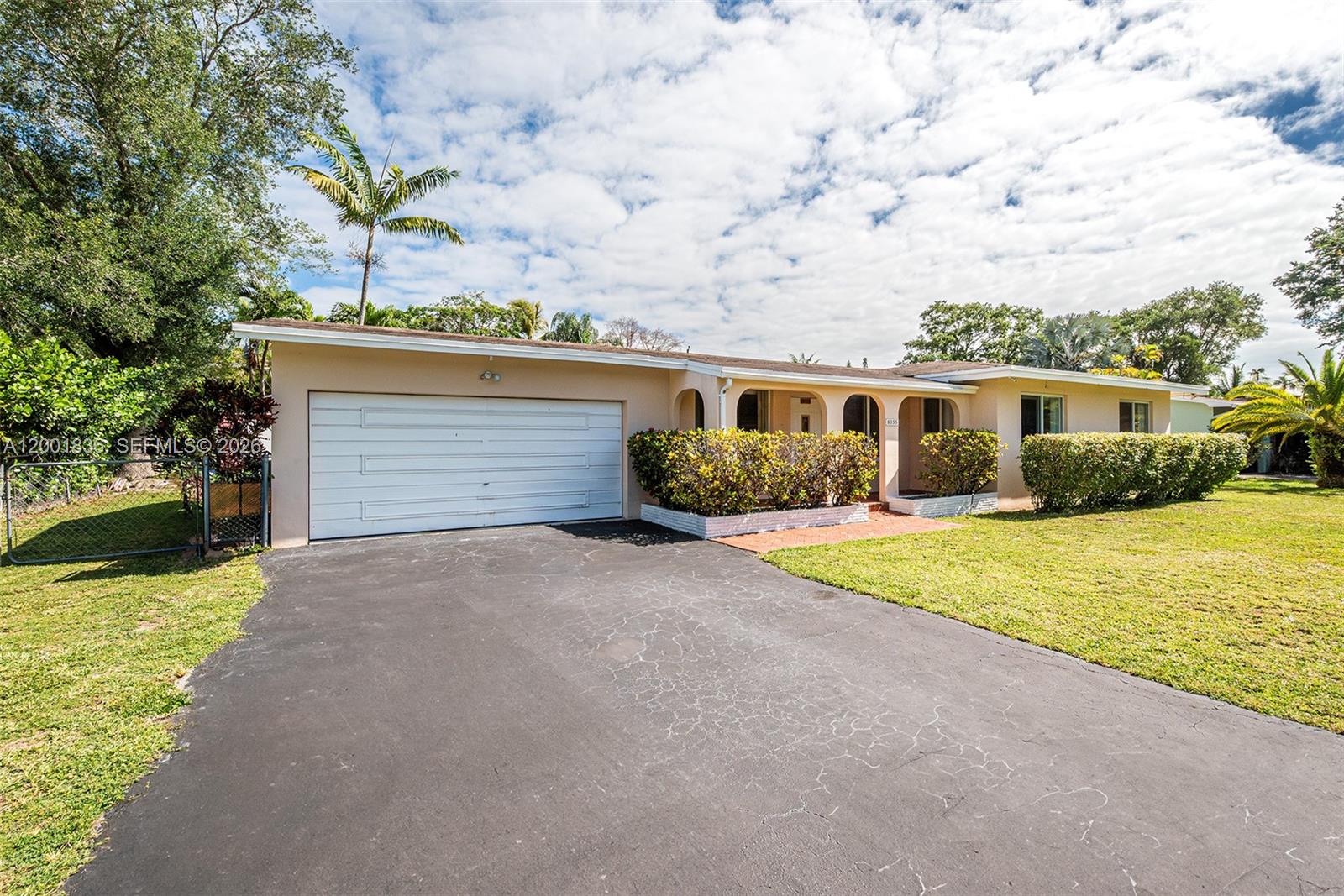 A single-story house features a white garage door, a covered entryway, and a paved driveway — 8355 SW 131st St, Pinecrest FL 33156, PINECREST, FL