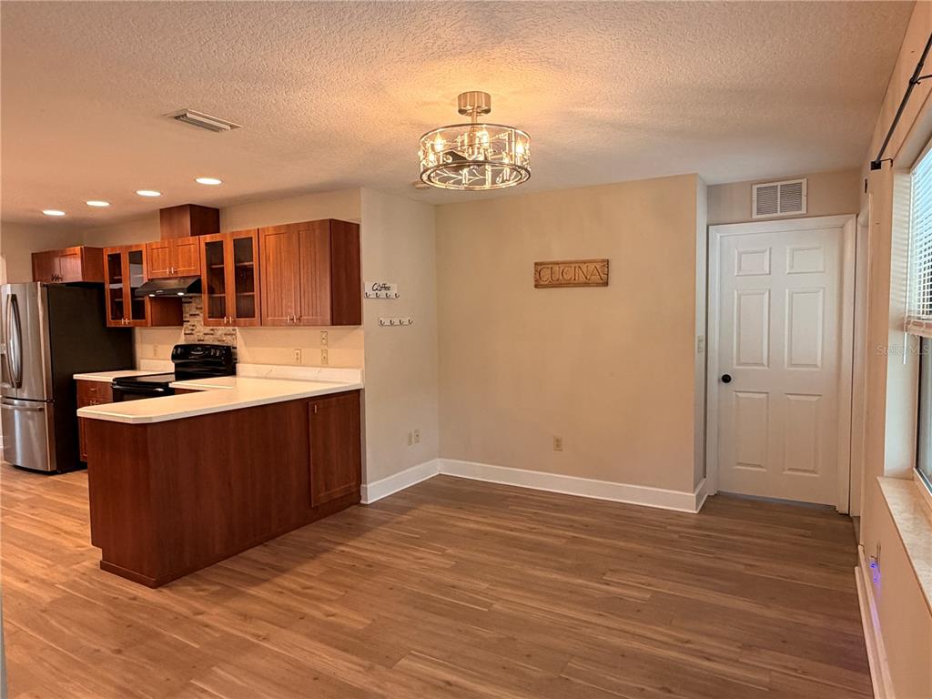 A kitchen with wood cabinets and a dining area featuring a chandelier and white door — 521 HIAWATHA AVENUE, INVERNESS, FL