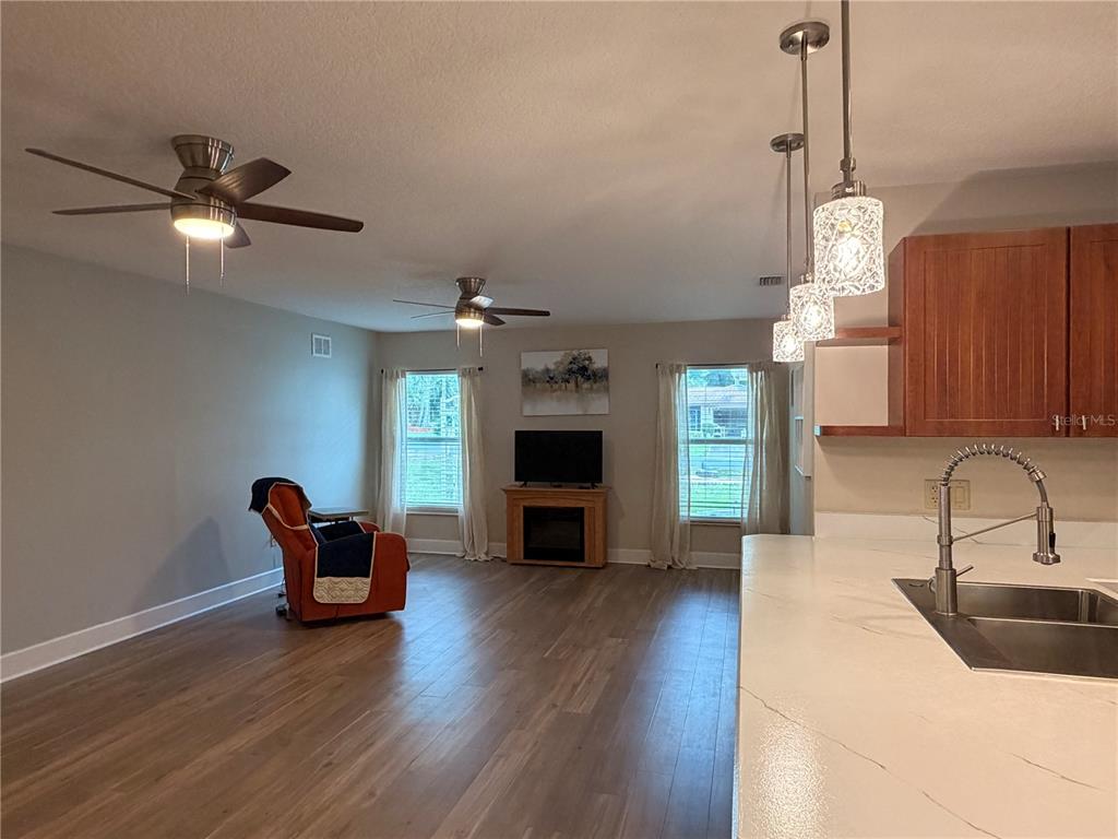 A kitchen features wood cabinets, white countertops, stainless steel appliances, and light wood flooring — 521 HIAWATHA AVENUE, INVERNESS, FL