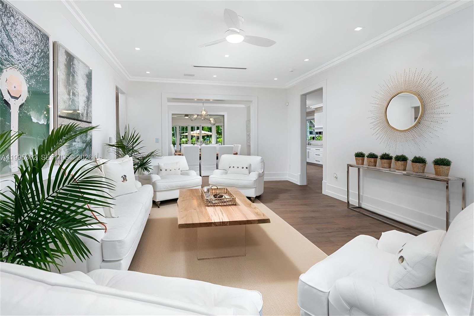 A bright living room features white furniture, a wooden coffee table, and dark wood floors — 2575 Pine Tree Dr, Miami Beach FL 33140, MIAMI BEACH, FL