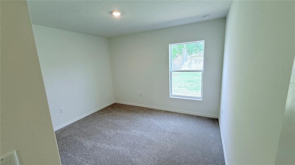 An empty bedroom features light-colored walls, gray carpeting, and a single window — 29 PERKINS LANE, PALM COAST, FL
