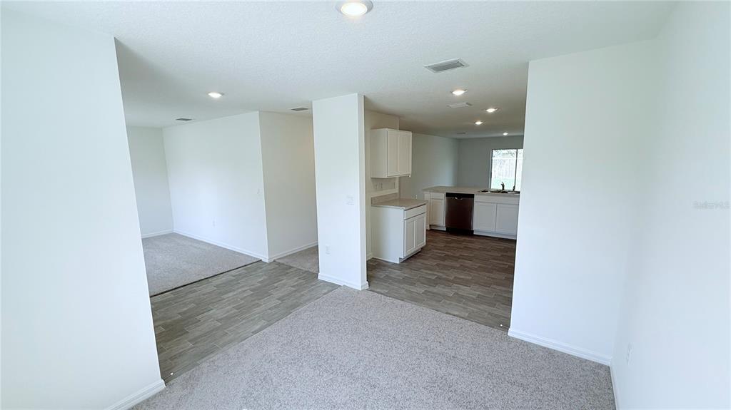 An open-concept interior features a carpeted living area, wood-look flooring, and a kitchen with white cabinets — 29 PERKINS LANE, PALM COAST, FL