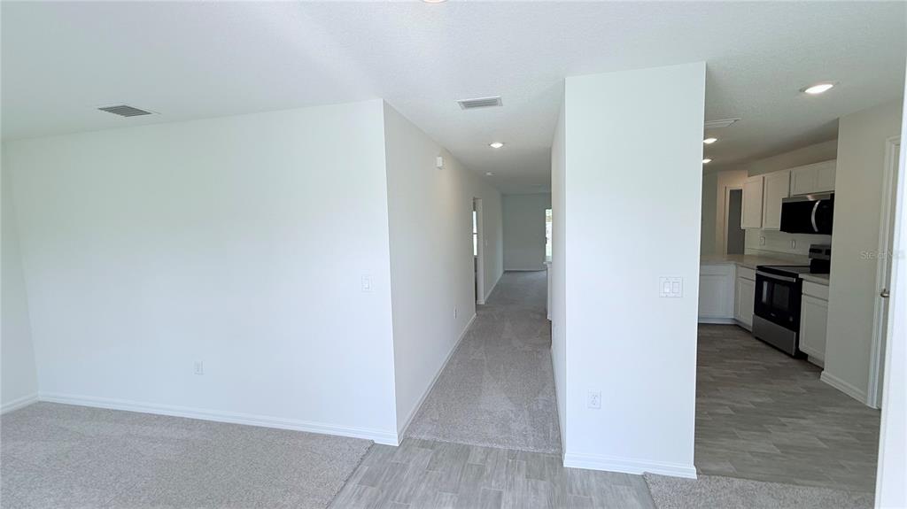 A view from a carpeted room looking toward a hallway and a white kitchen — 29 PERKINS LANE, PALM COAST, FL