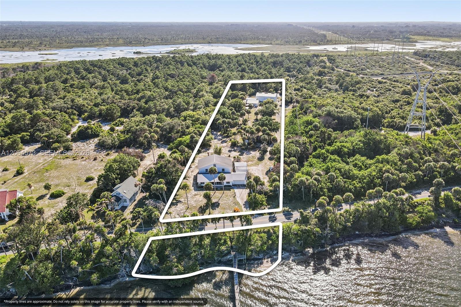 An aerial view shows a house and outbuilding on a wooded lot near water — 7802 Indian River Drive Dr S, Fort Pierce FL 34982, FORT PIERCE, FL