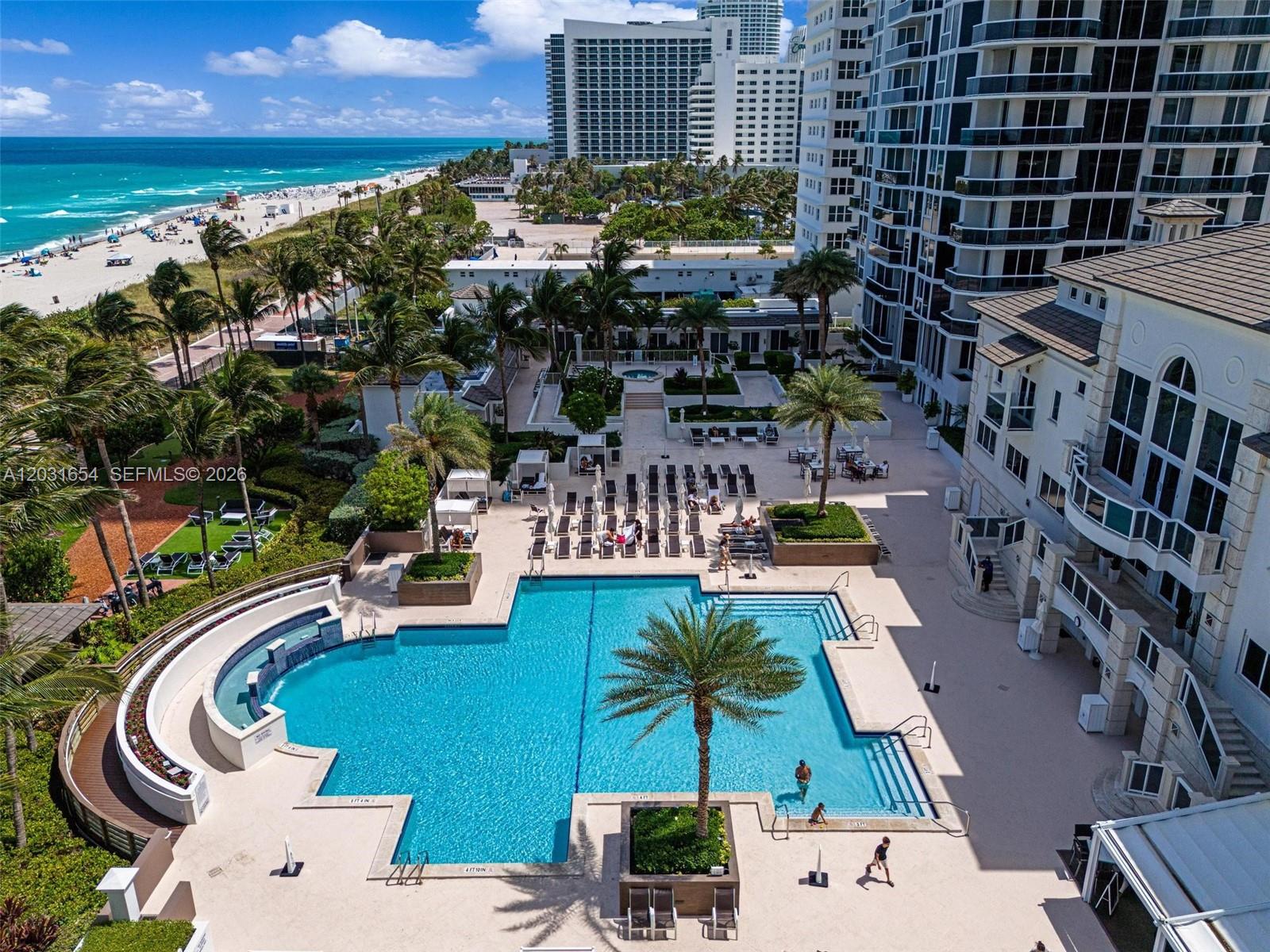 An aerial view shows a swimming pool with a palm tree, lounge chairs, and beach access — 4779 Collins Ave # 2305, Miami Beach FL 33140, MIAMI BEACH, FL