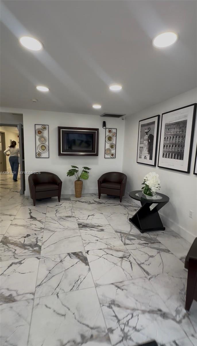 A lobby features two dark leather armchairs, a small round table, and marble-patterned tile flooring — 175 Fontainebleau Blvd, Miami FL 33172, MIAMI, FL