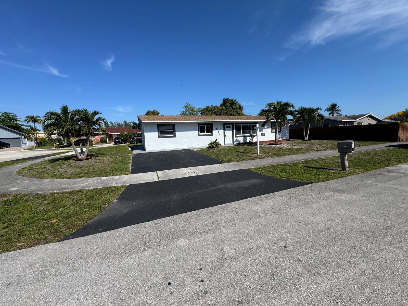 A single-story white house with a brown roof and a paved driveway under a blue sky — 4010 NE 6th Avenue, Deerfield Beach FL 33064, DEERFIELD BEACH, FL