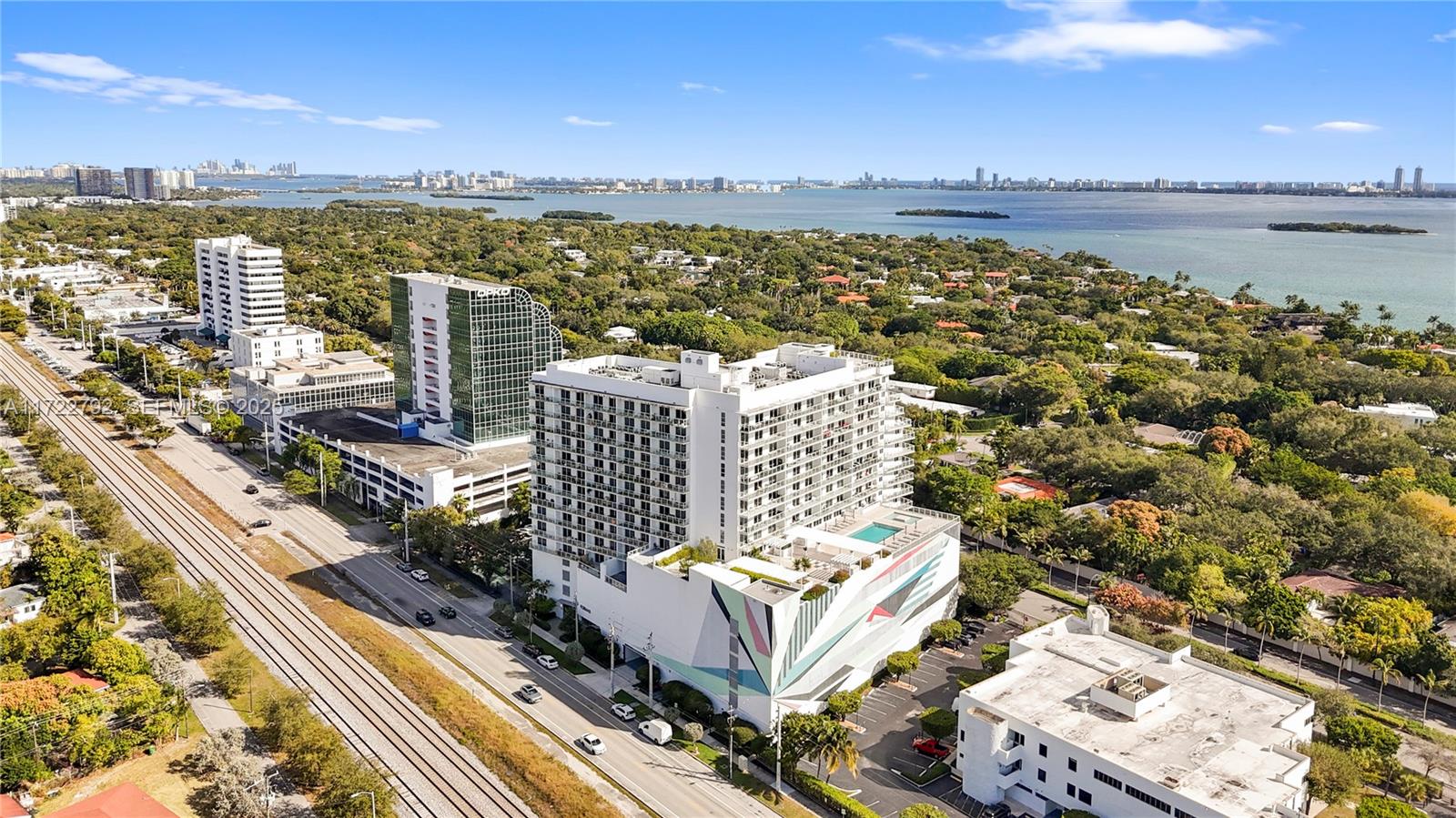 An aerial view shows a large white apartment building with a mural next to railroad tracks — 4250 Biscayne Blvd # 1418, Miami FL 33137, MIAMI, FL