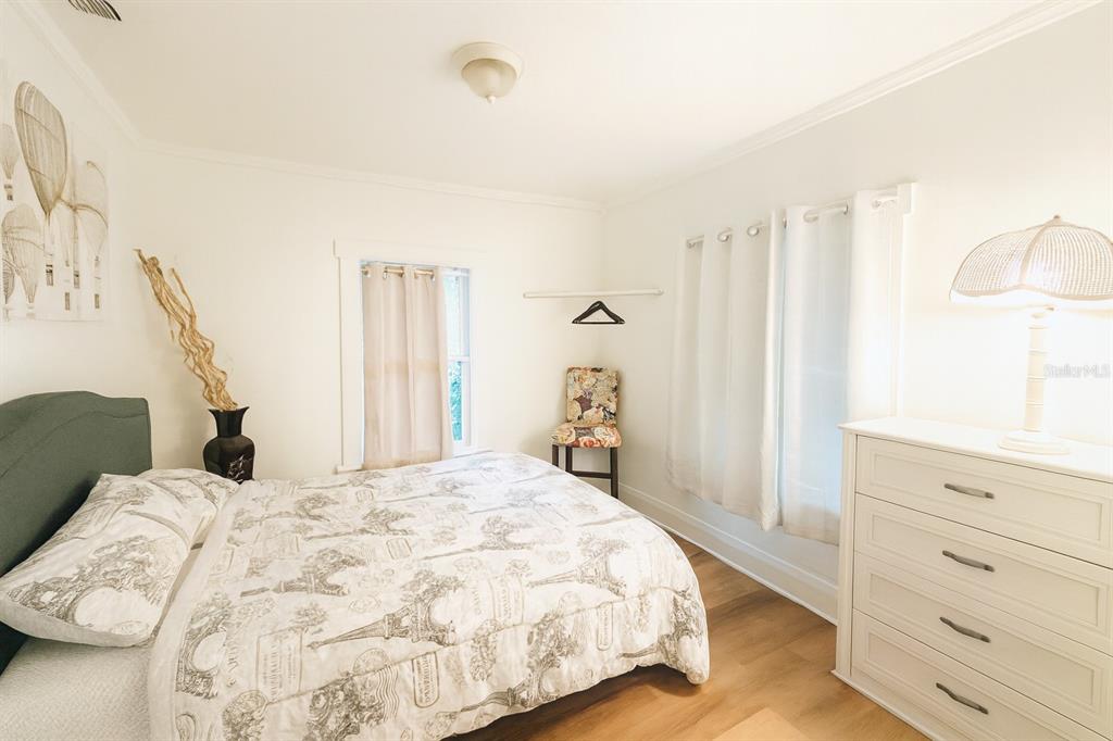 A bedroom features a bed with patterned bedding, a white dresser, and a window — 7105 N 10TH STREET, TAMPA, FL