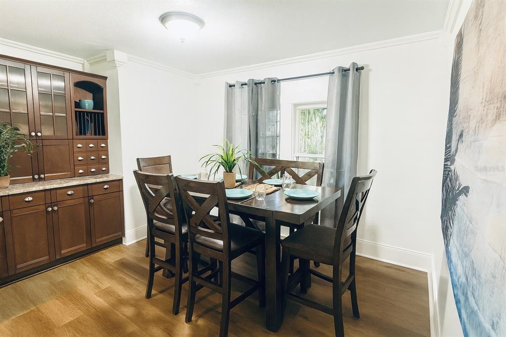 A dining room features a dark wood table with chairs, a matching hutch, and curtains — 7105 N 10TH STREET, TAMPA, FL