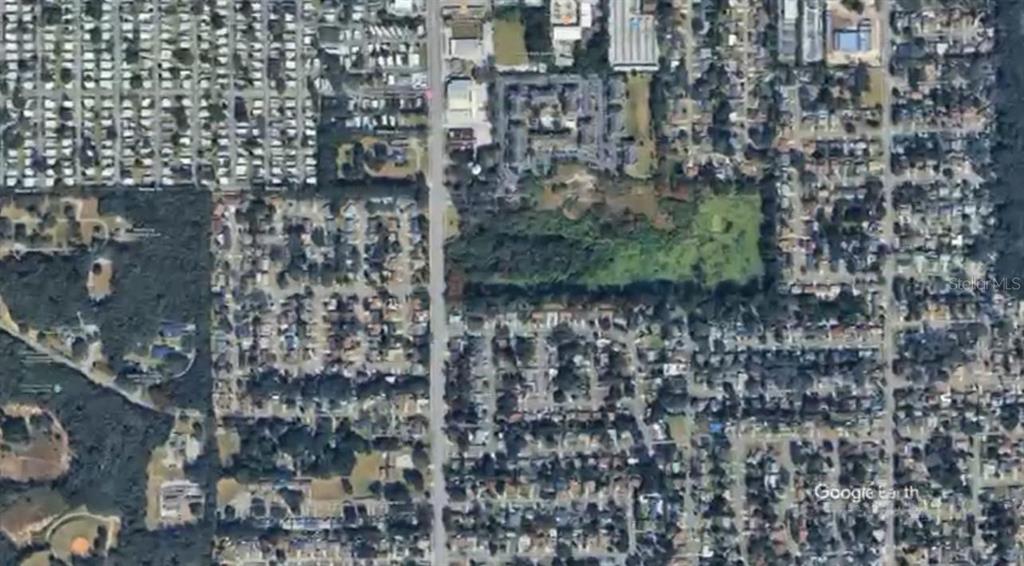 This is an aerial satellite view of a residential neighborhood with a central wooded lot — HIAWASSEE ROAD, ORLANDO, FL