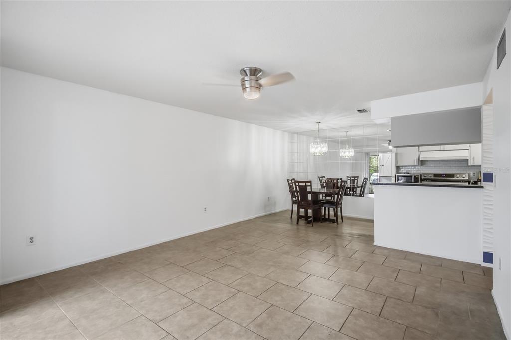 A dining area with tile floors and a mirrored wall sits adjacent to a kitchen — 2715 72ND STREET COURT W, BRADENTON, FL