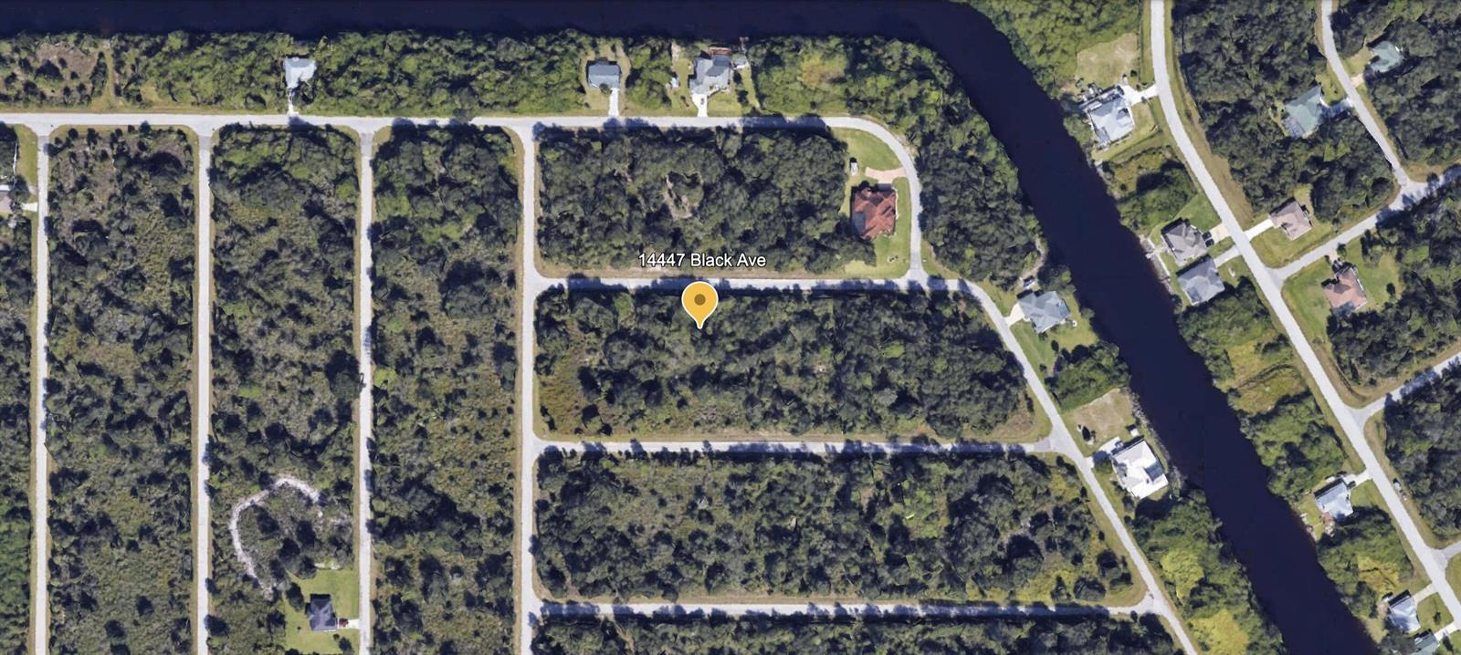 This aerial map view shows a vacant, wooded residential lot in a suburban neighborhood — 14447 Black Avenue, FL 33953, FL