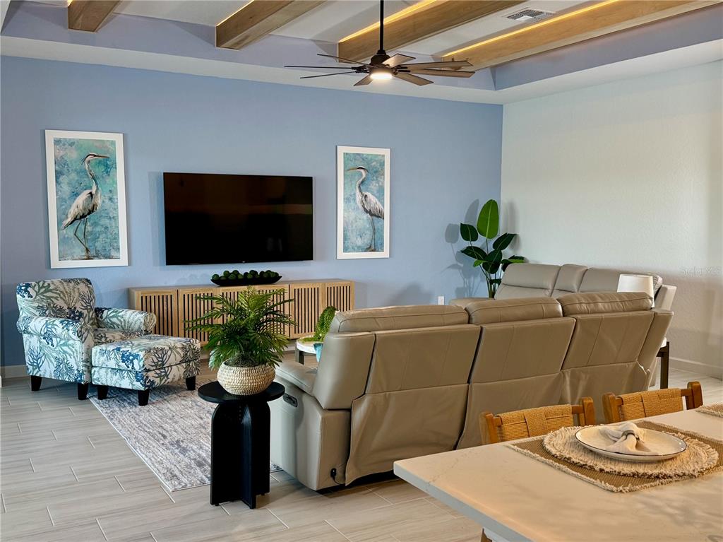 A modern kitchen features white cabinetry, a large quartz island with seating, and stainless appliances — 5612 LIGHTNING WHELK LANE, LAKEWOOD RANCH, FL