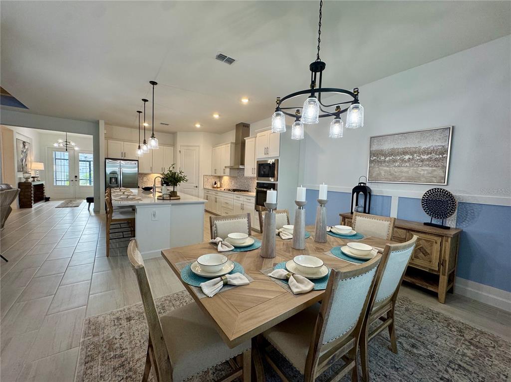 A living room features a light blue wall, a large television, and a beige leather sofa — 5612 LIGHTNING WHELK LANE, LAKEWOOD RANCH, FL