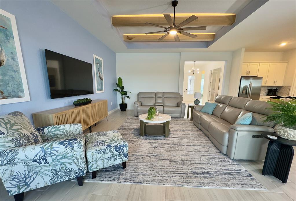 A dining area with a wooden table and chandelier opens into a modern white kitchen — 5612 LIGHTNING WHELK LANE, LAKEWOOD RANCH, FL