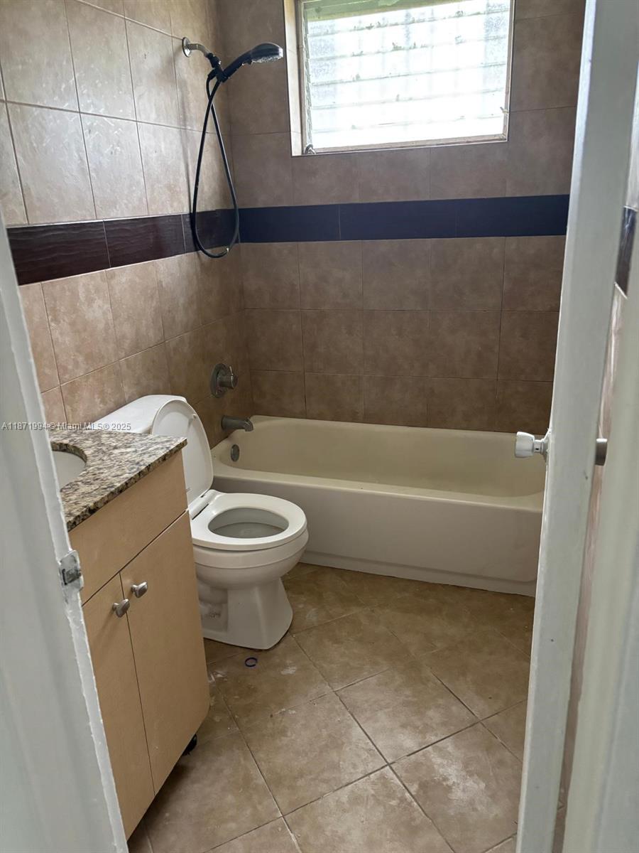 A bathroom features a vanity, a toilet, and a bathtub with tiled walls — 5100 NW 23rd Ave # 1, Miami FL 33142, MIAMI, FL