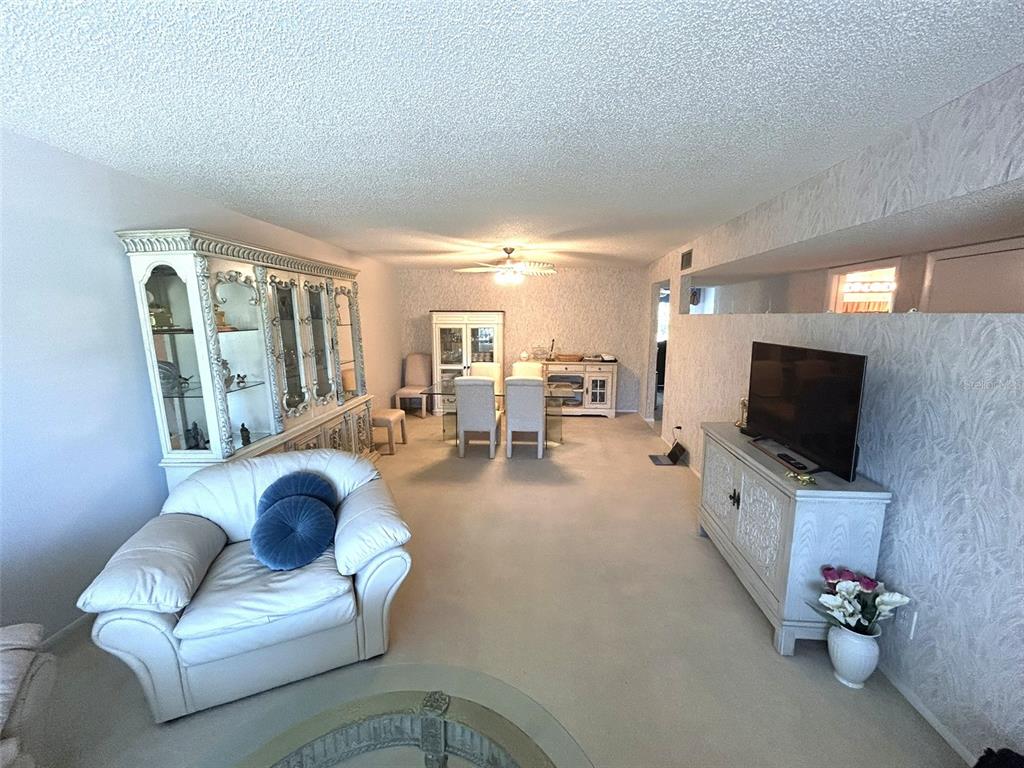 A living and dining area features white furniture, beige carpeting, and textured walls — 2170 AMERICUS BOULEVARD S UNIT 57, CLEARWATER, FL