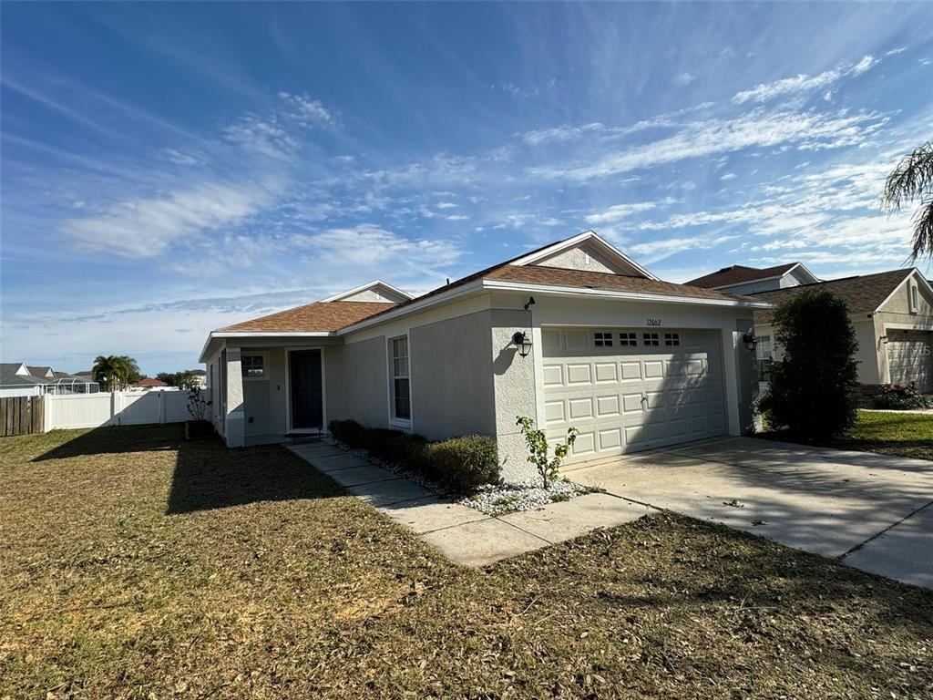 A single-story house with a beige stucco exterior, a two-car garage, and a concrete walkway — 12602 EVINGTON POINT DRIVE, RIVERVIEW, FL
