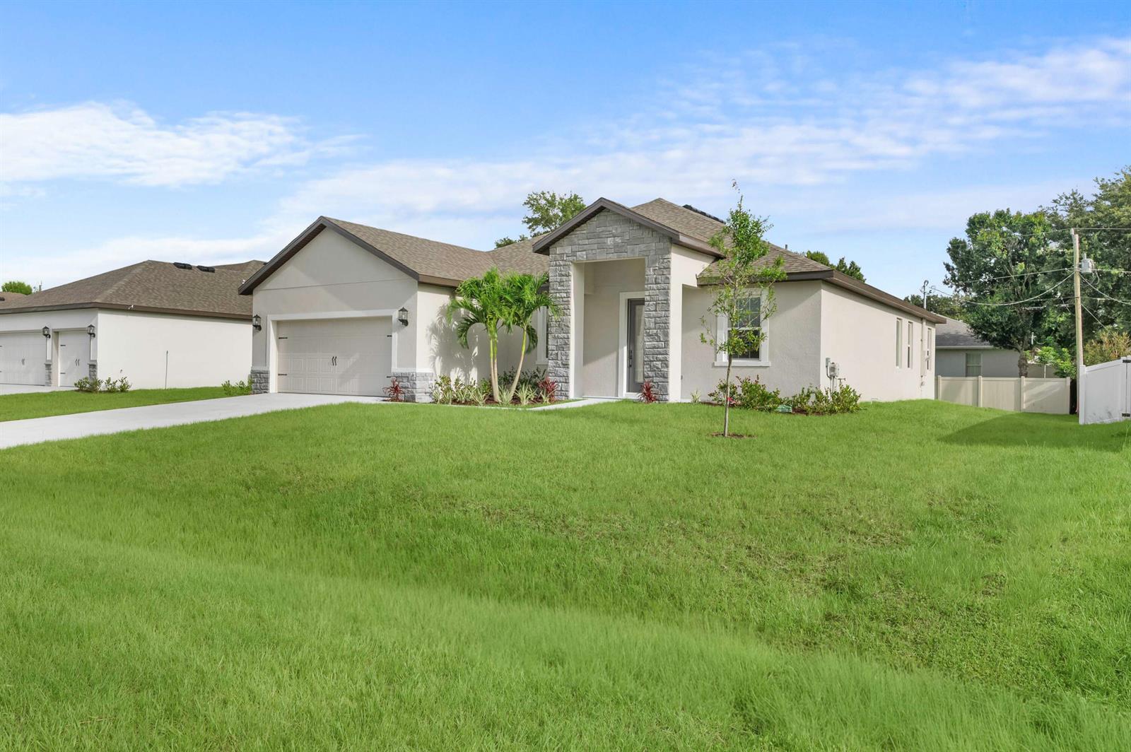 A single-story house with a beige stucco exterior, stone accents, and a two-car garage — 8016 102nd Court, Vero Beach FL 32967, VERO BEACH, FL
