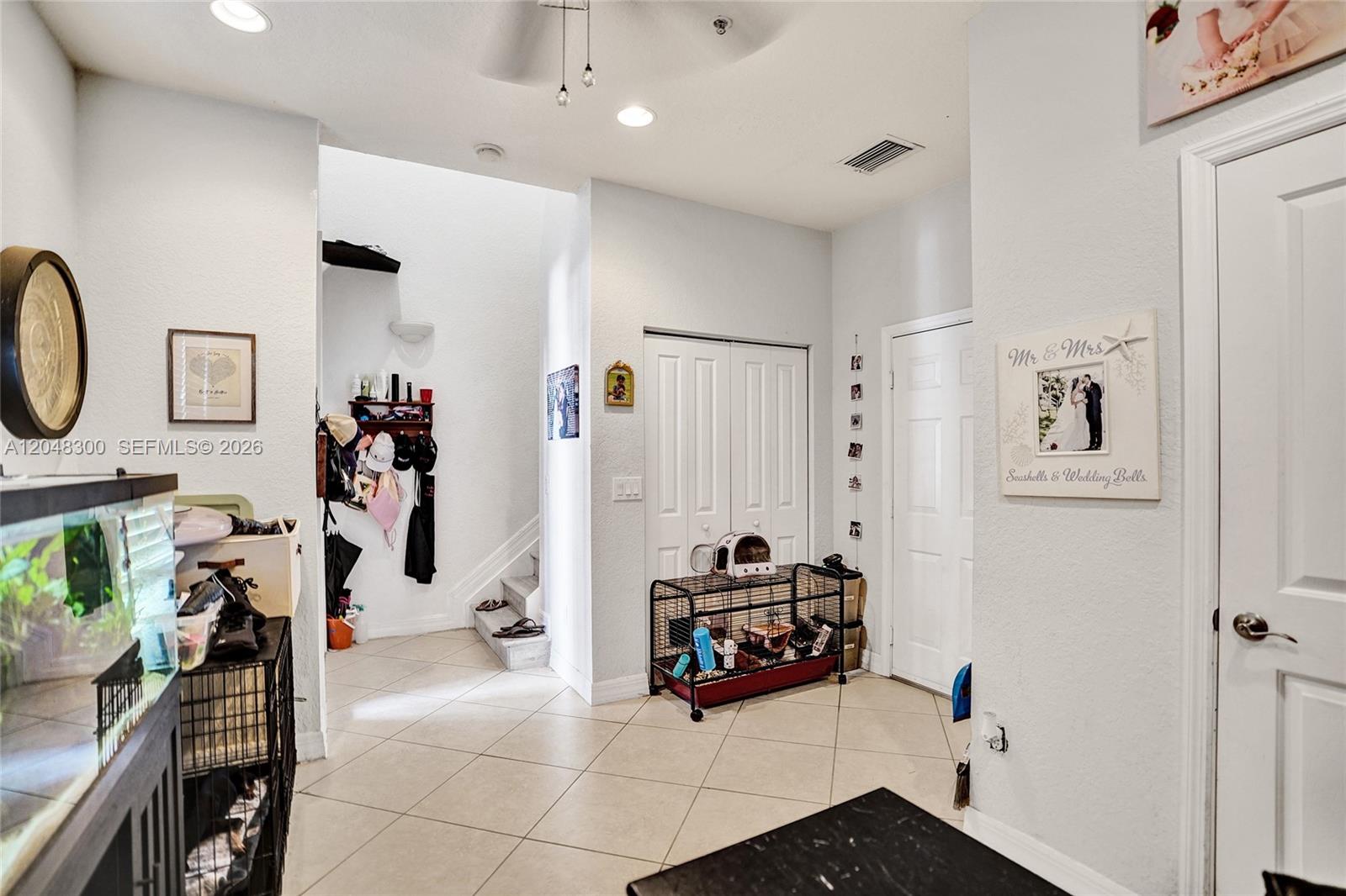 An entryway features tile flooring, a staircase, white doors, and pet enclosures — 132 Ocean Cay Way, Hypoluxo FL 33462, HYPOLUXO, FL