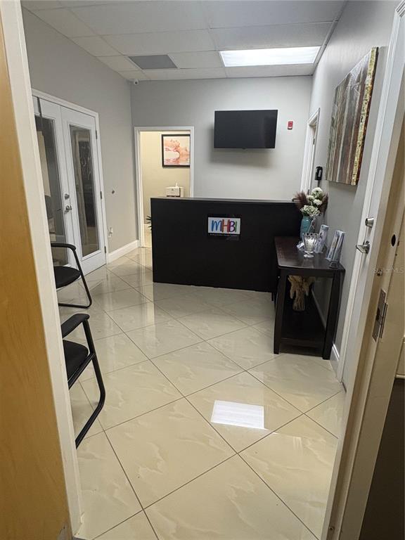 A reception area features a dark desk with a logo, tile flooring, and two chairs — 12701 S JOHN YOUNG PARKWAY UNIT 212, ORLANDO, FL