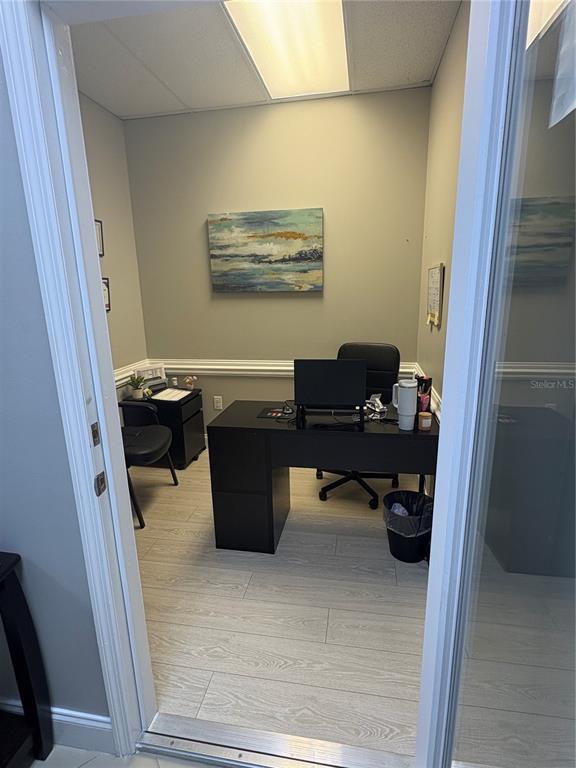 A small office features a black desk, a rolling chair, and a landscape painting — 12701 S JOHN YOUNG PARKWAY UNIT 212, ORLANDO, FL