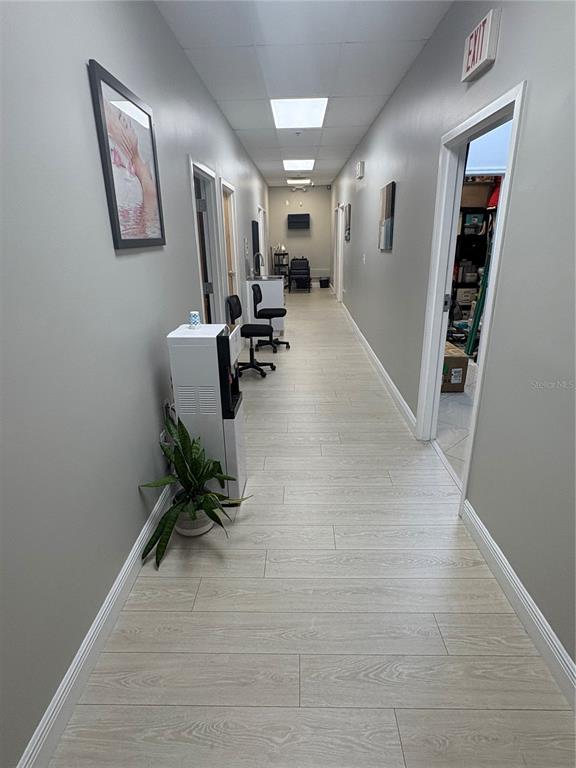 A long, narrow hallway features light wood-look flooring, gray walls, and several doorways — 12701 S JOHN YOUNG PARKWAY UNIT 212, ORLANDO, FL