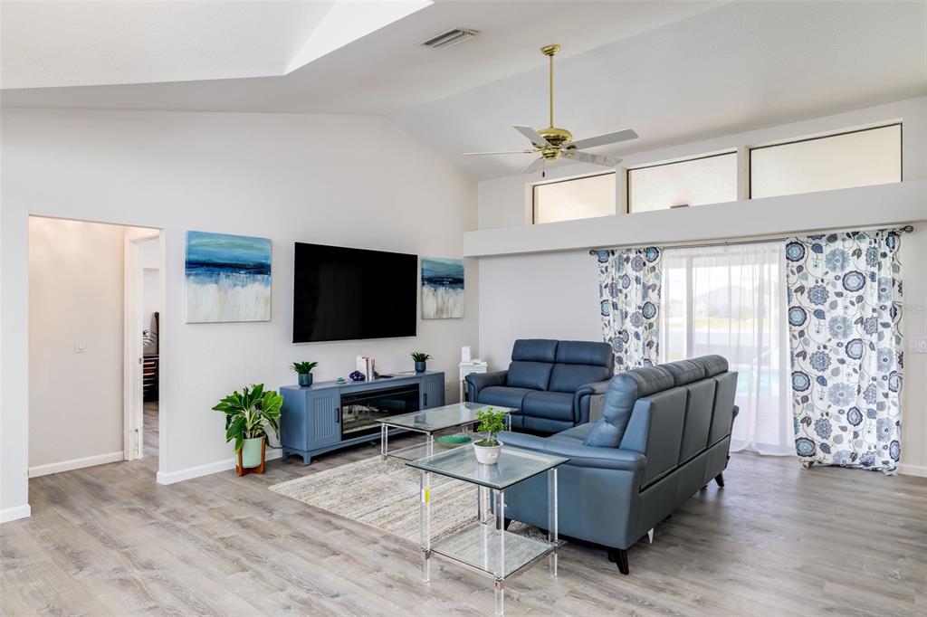 A living room features a vaulted ceiling, blue leather furniture, and a wall-mounted television — 2250 RIO DE JANEIRO AVENUE, PUNTA GORDA, FL