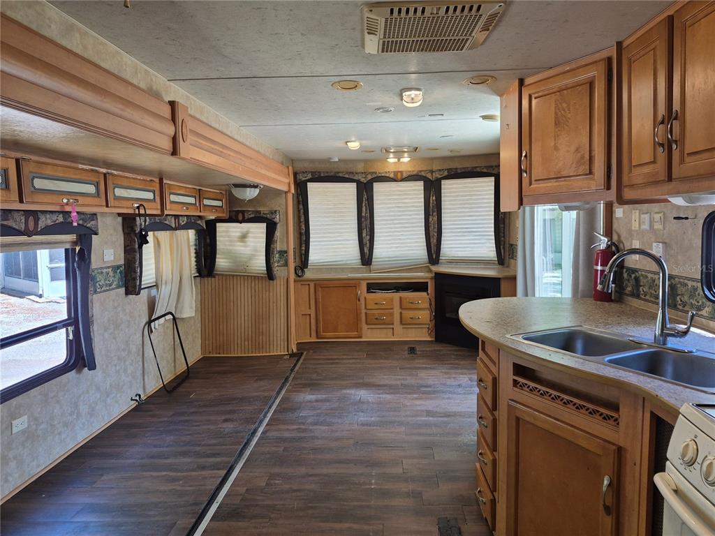 An interior view of a travel trailer featuring wood cabinets, dark flooring, and a kitchen sink — 3000 CLARCONA ROAD UNIT 530, APOPKA, FL