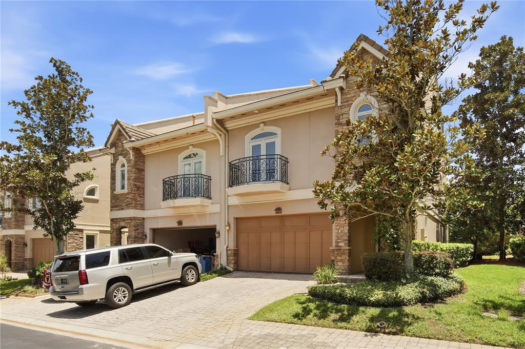 A two-story townhouse with a stone facade, two balconies, and a paved driveway with a car — 1465 HILLSIDE LANDING DRIVE, TARPON SPRINGS, FL