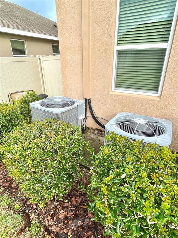Two air conditioning units sit on a concrete pad outside a tan stucco house — 21648 SOUTHERN CHARM DRIVE, LAND O LAKES, FL