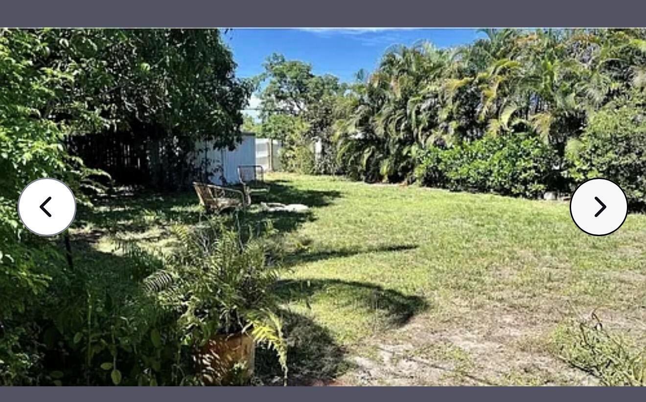 A grassy backyard features a metal shed, mature trees, and two outdoor chairs — 24 SW 12th Street, Dania Beach FL 33004, DANIA BEACH, FL