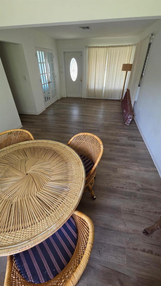 A dining area with a round wicker table and chairs features light wood-look flooring — 24 SW 12th Street, Dania Beach FL 33004, DANIA BEACH, FL