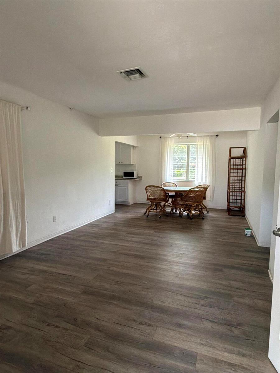 A dining area with wicker chairs and a table sits adjacent to a small kitchen — 24 SW 12th Street, Dania Beach FL 33004, DANIA BEACH, FL