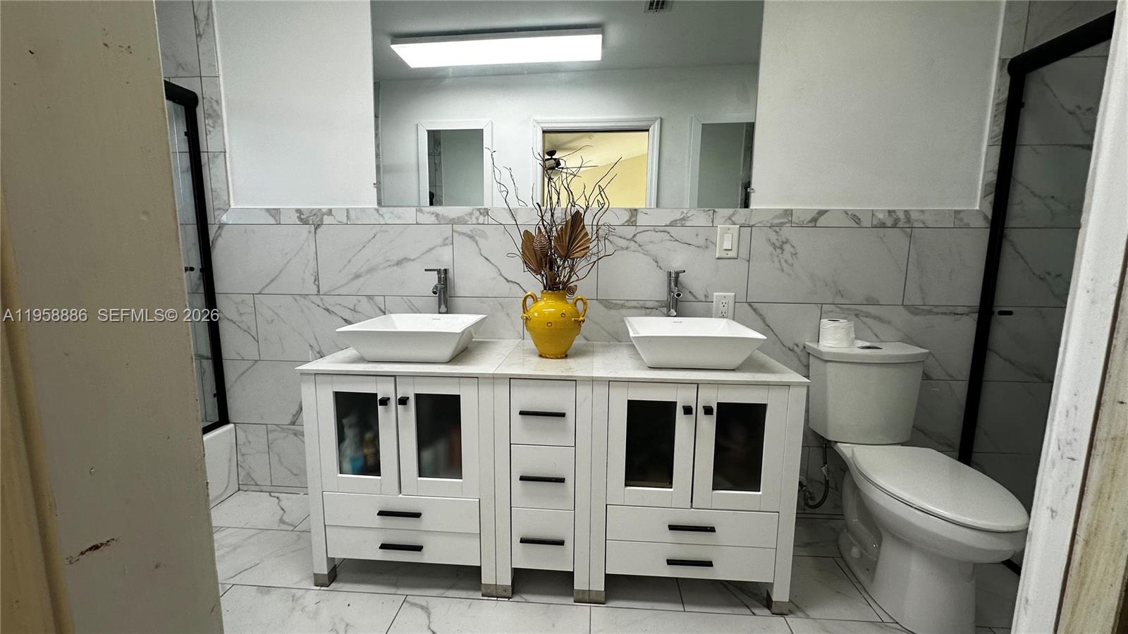 A bathroom features a double vanity with vessel sinks, marble-look tile walls, and a toilet — 4465 SW 38th Ter, Dania Beach FL 33312, DANIA BEACH, FL