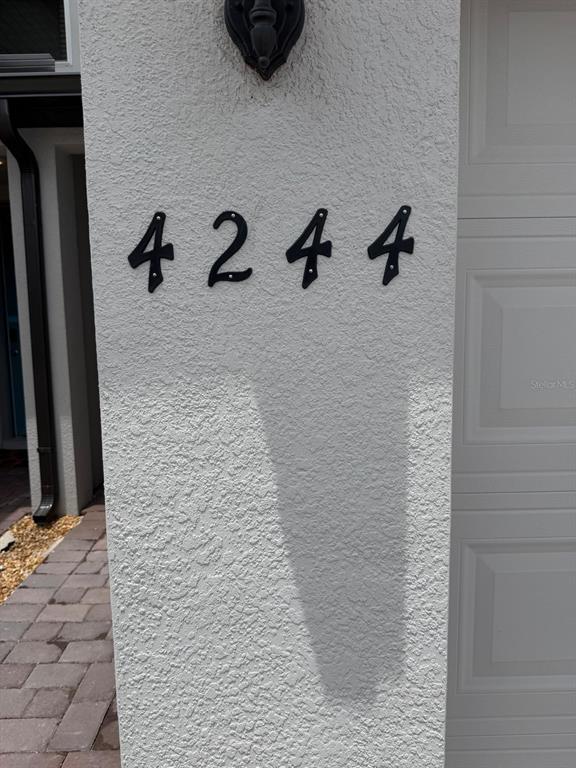 Black house numbers are mounted on the white stucco exterior wall next to a garage — 4244 RANCH HOUSE ROAD, ST CLOUD, FL
