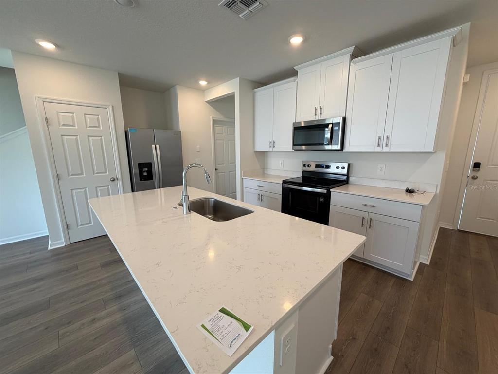 A kitchen features a white quartz island, stainless steel appliances, and white cabinetry — 4244 RANCH HOUSE ROAD, ST CLOUD, FL