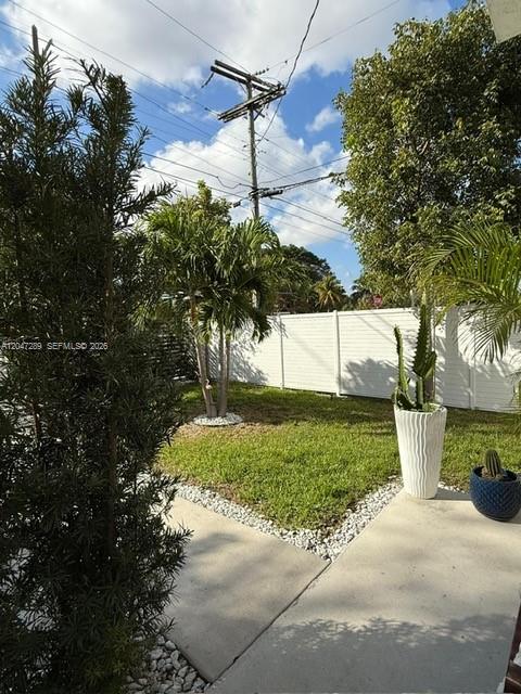 A white fence encloses a grassy yard with palm trees and potted plants — 5629 NW 31st Ave, Miami FL 33142, MIAMI, FL