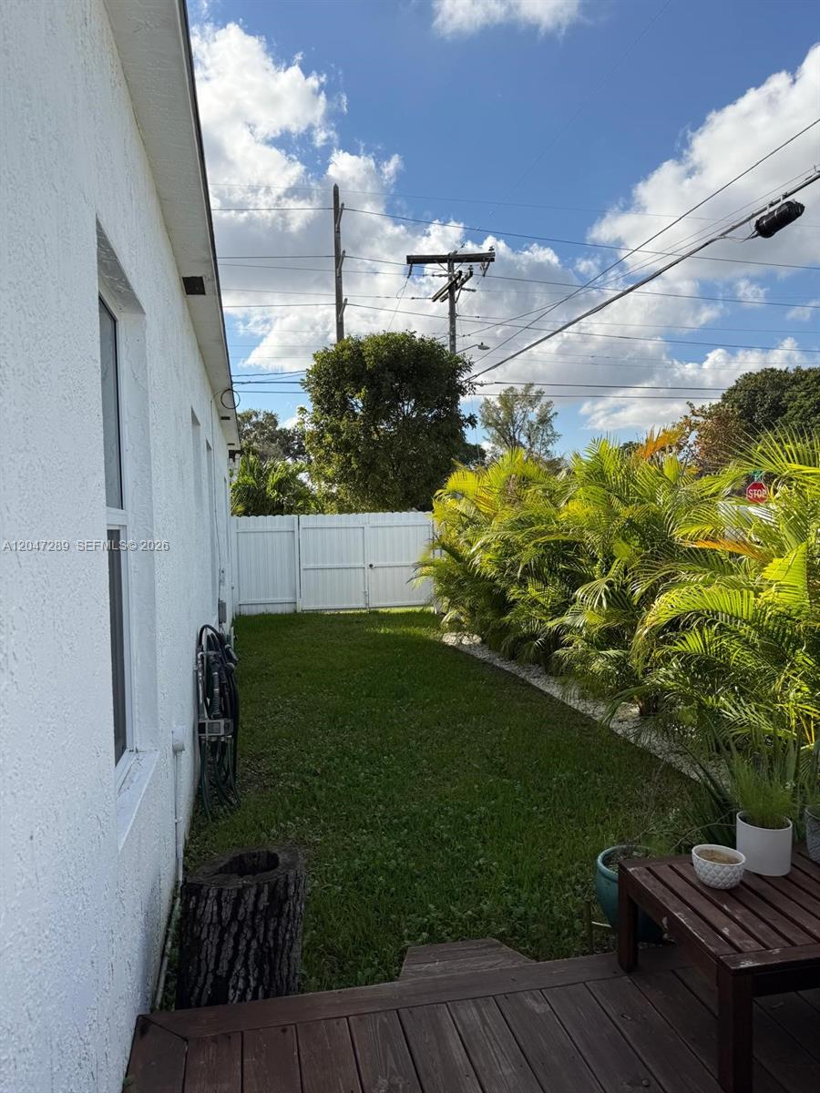A side yard features a white fence, a grassy lawn, and a row of palm trees — 5629 NW 31st Ave, Miami FL 33142, MIAMI, FL