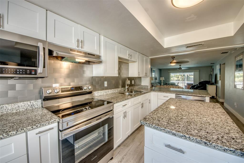 A modern kitchen features white cabinets, granite countertops, stainless steel appliances, and a central island — 912 SE 24TH AVENUE UNIT A &  B, CAPE CORAL, FL