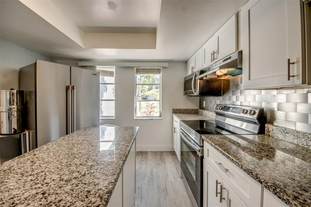 A kitchen features white cabinets, granite countertops, stainless steel appliances, and a central island — 912 SE 24TH AVENUE UNIT A &  B, CAPE CORAL, FL