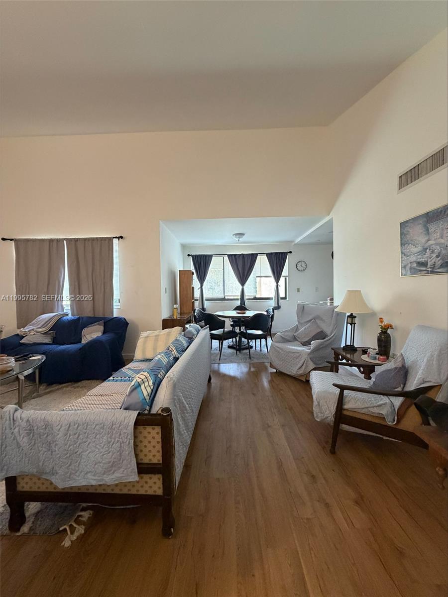 A living room with wood flooring, vaulted ceilings, and a dining area in the background — 221 W Park Dr # 3, Miami FL 33172, MIAMI, FL