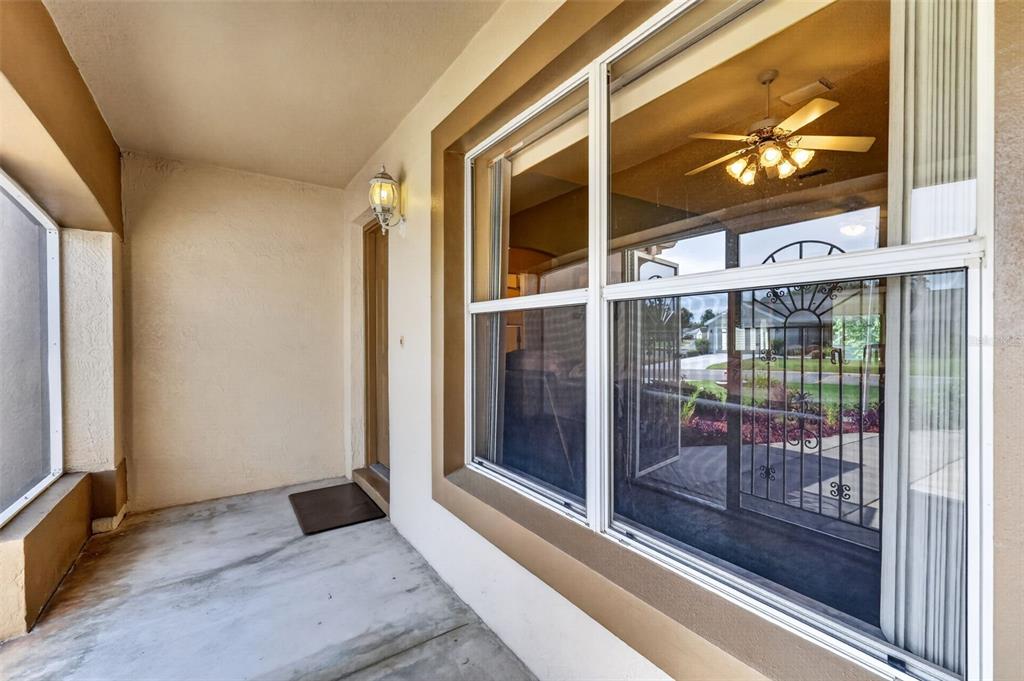 A covered patio features a concrete floor, a wall-mounted light, and a large window — 1911 DEL NORTE DRIVE, THE VILLAGES, FL