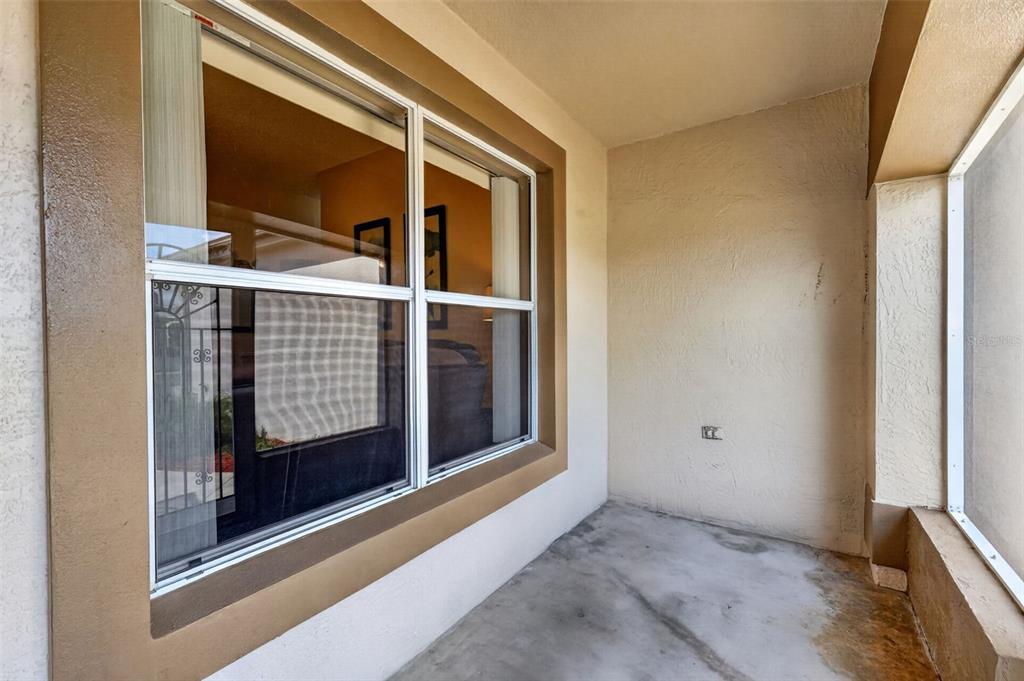 A covered patio features a large window, a concrete floor, and a screened enclosure — 1911 DEL NORTE DRIVE, THE VILLAGES, FL