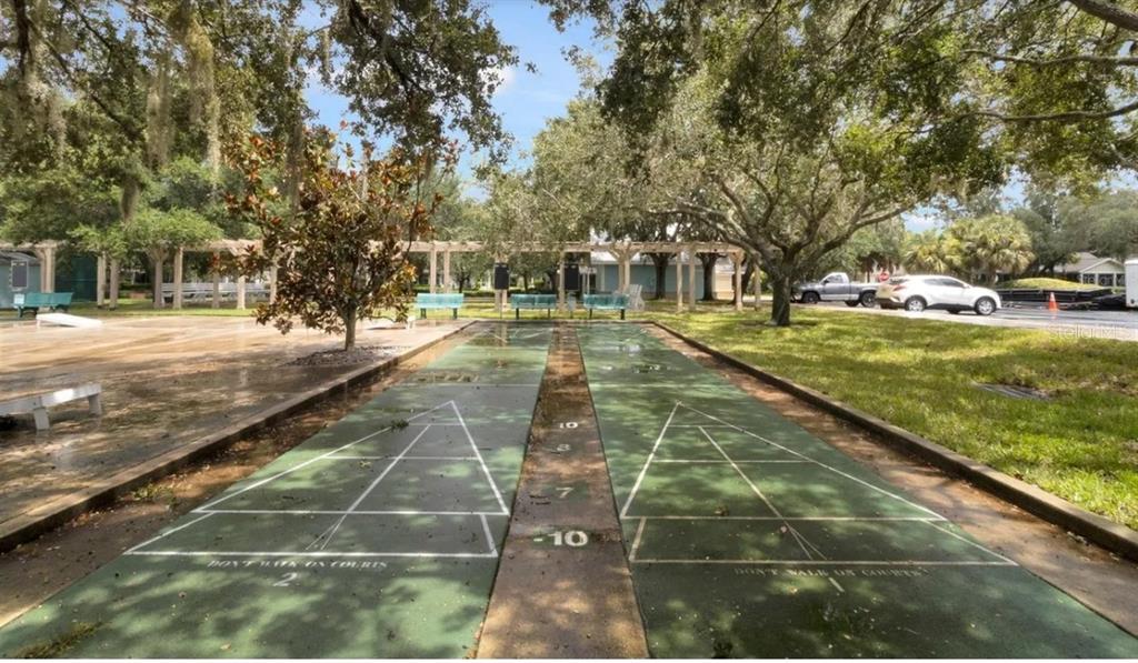 Two outdoor shuffleboard courts are situated in a park-like setting with trees and benches — 19335 WATER OAK DRIVE UNIT 108, PORT CHARLOTTE, FL