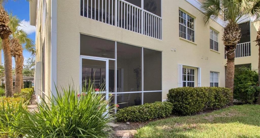A ground-floor condo unit features a screened-in patio and palm trees in a landscaped yard — 19335 WATER OAK DRIVE UNIT 108, PORT CHARLOTTE, FL
