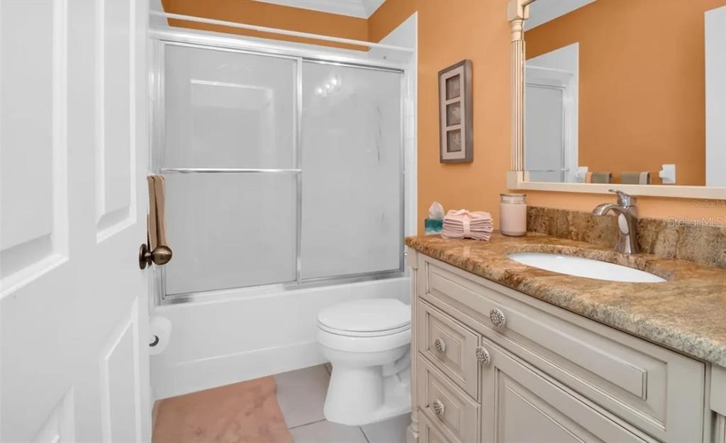 A bathroom features a vanity with a granite countertop, a toilet, and a shower-tub combo — 19335 WATER OAK DRIVE UNIT 108, PORT CHARLOTTE, FL